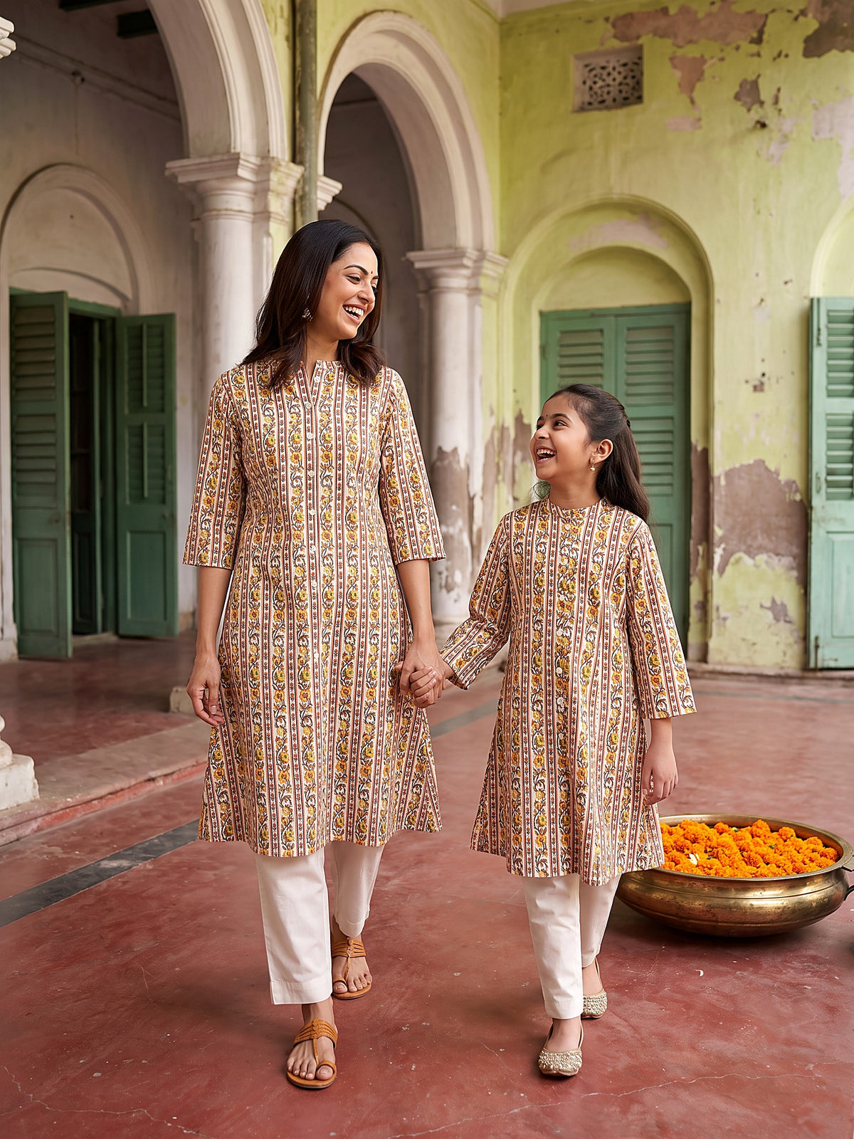 Mother and daughter walking hand in hand in matching kurtis