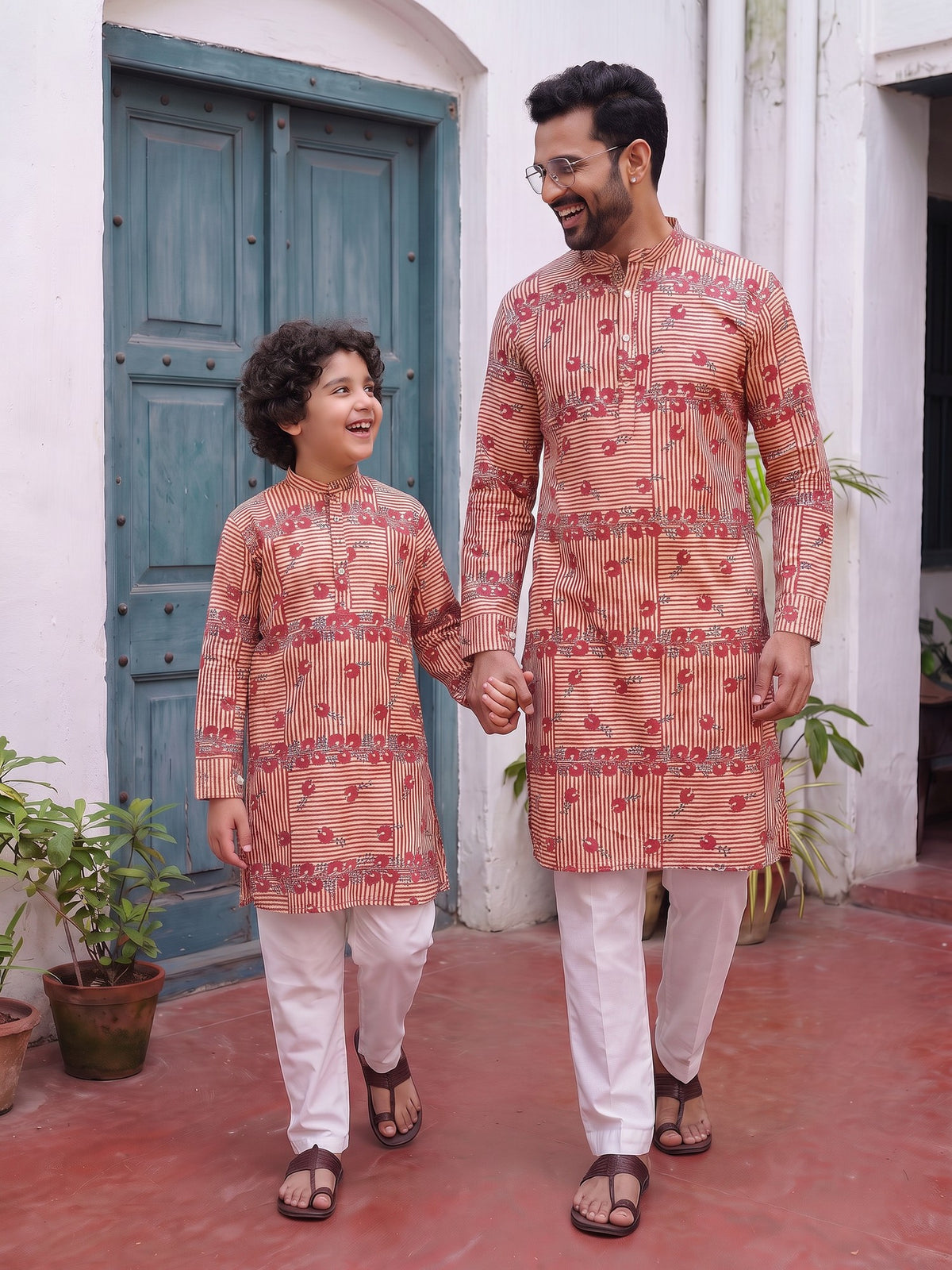 Father and son walking hand in hand in red stripe kurtas