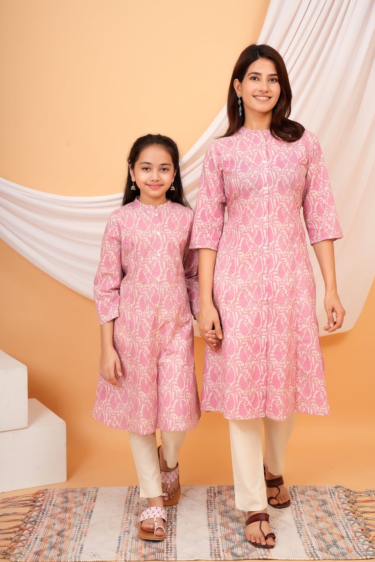 Mother and daughter walking hand in hand in pink paisley kurtis