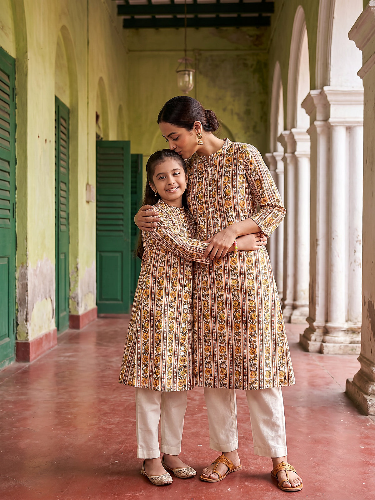 Mother hugging daughter in ivory and yellow kurtis