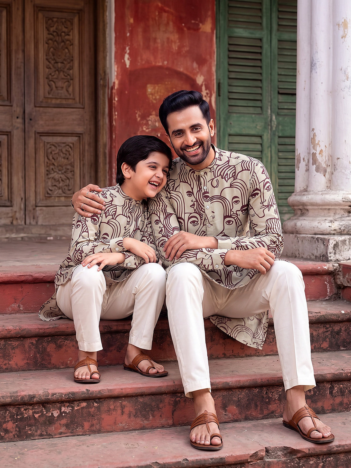 Father and son sitting on steps in matching face art kurtas