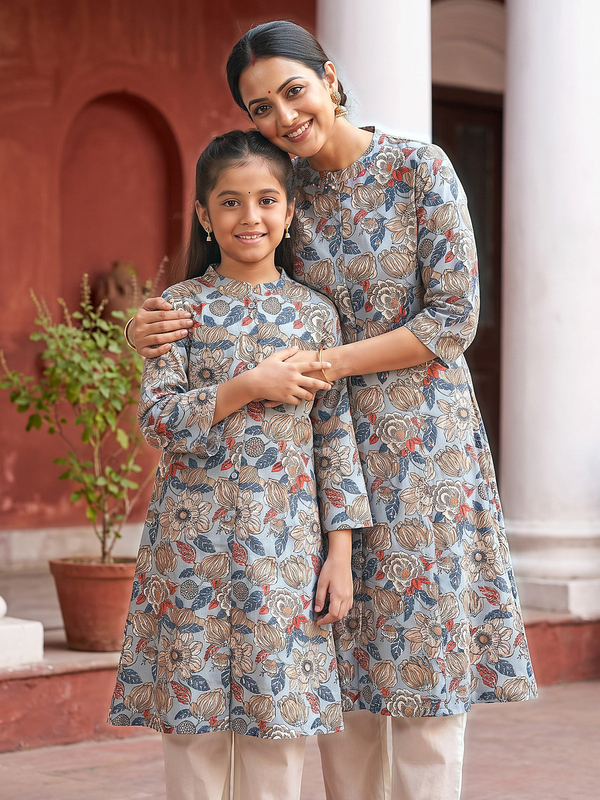 Mother hugging daughter in matching grey floral kurtis