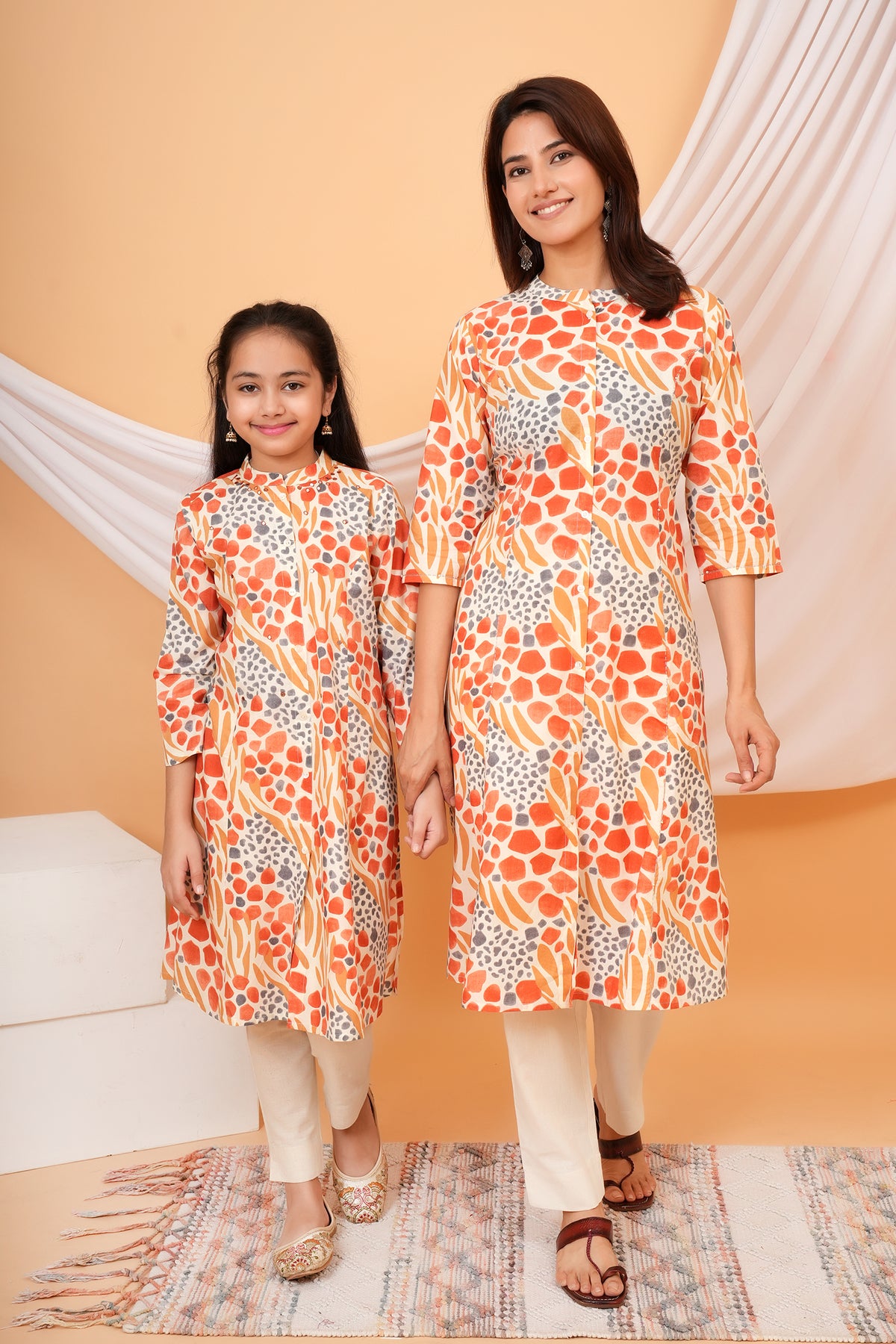 Maa and Beti in matching orange abstract animal printed kurtis