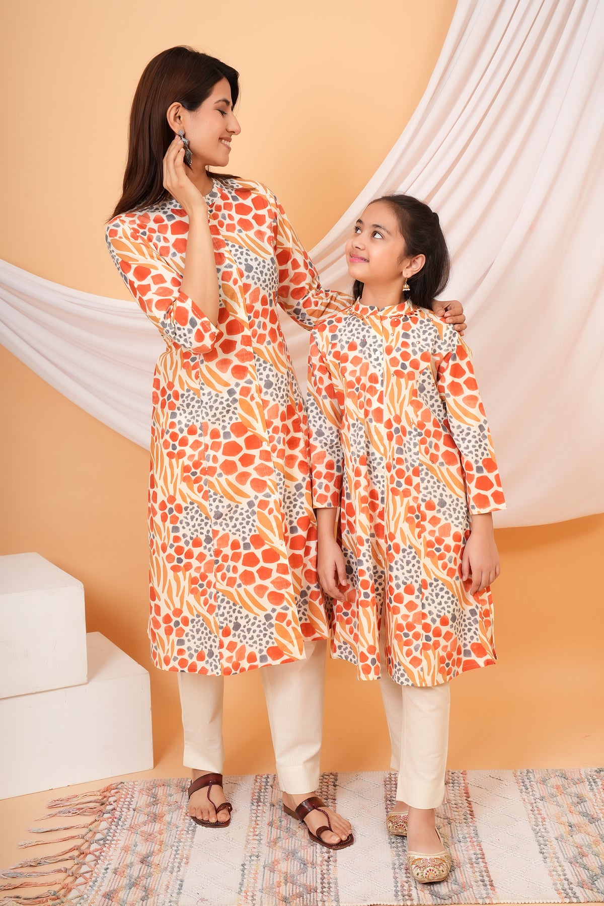 Maa and Beti in matching orange abstract animal printed kurtis