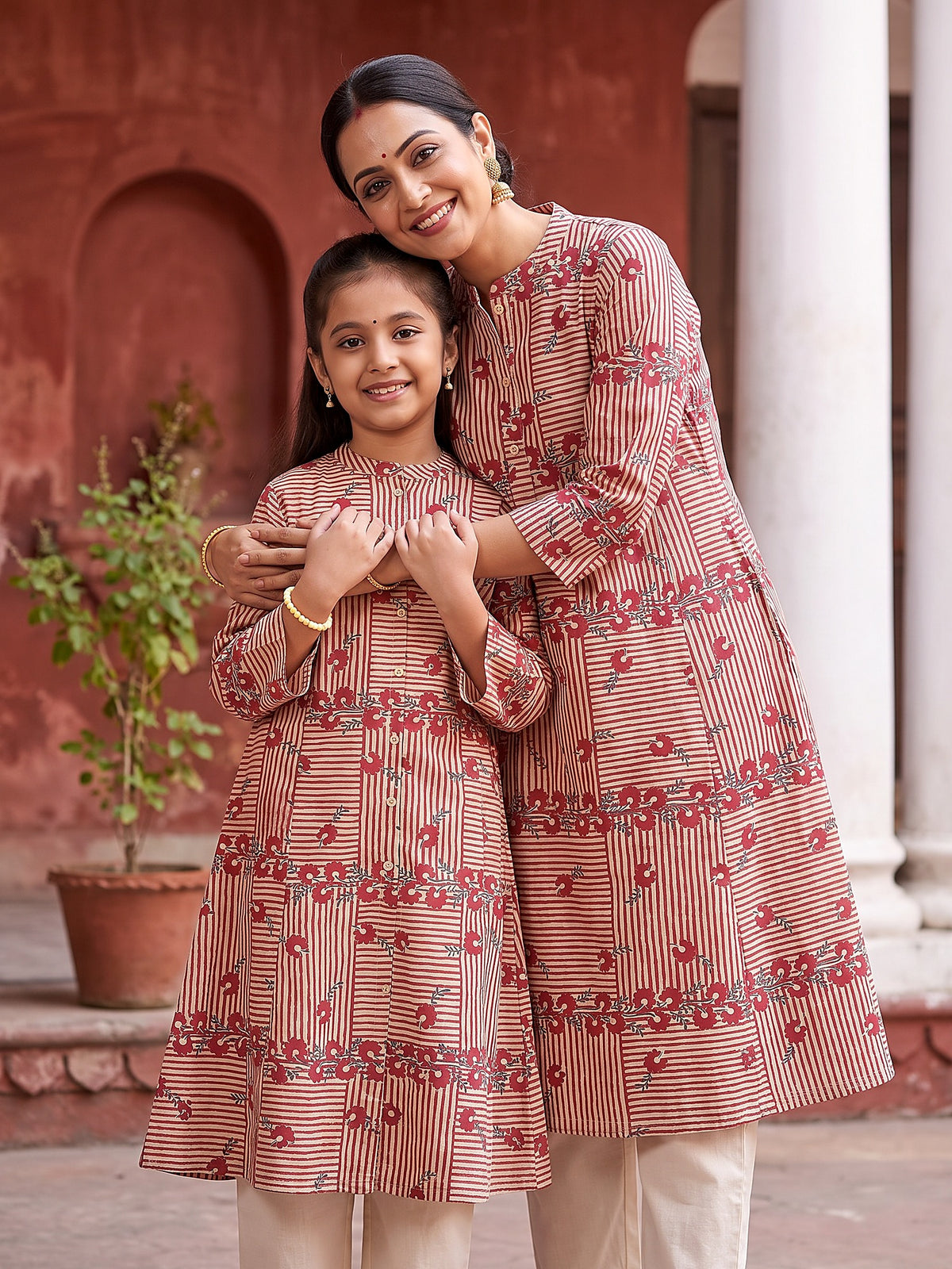 Mother hugging daughter in matching red stripe kurtis
